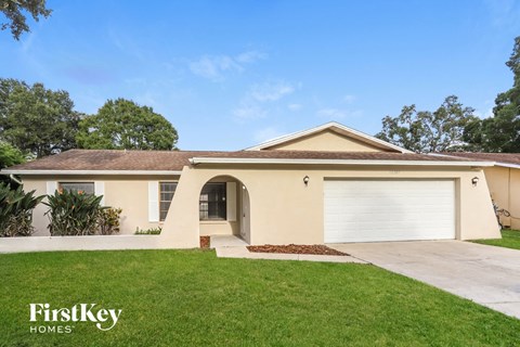 a beige house with a garage door and a lawn