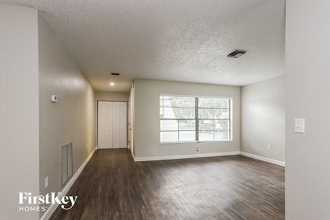 the living room of an empty house with wood flooring and a large window