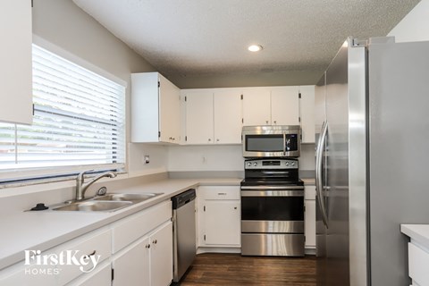 a kitchen with white cabinets and stainless steel appliances and a window