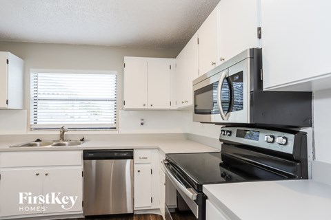 a kitchen with white cabinets and stainless steel appliances and a sink
