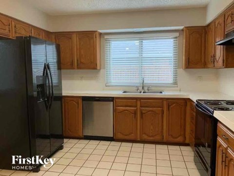 A kitchen with wooden cabinets and a black fridge.