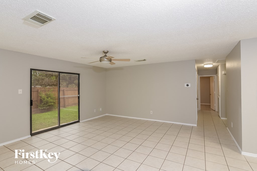 an empty living room with a ceiling fan and a sliding glass door