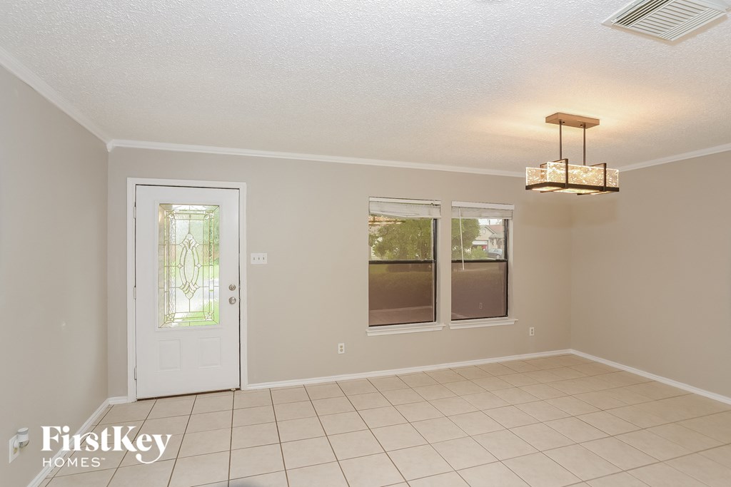an empty dining room with a door and a chandelier