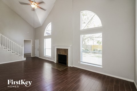 A spacious living room with a fireplace and a staircase.