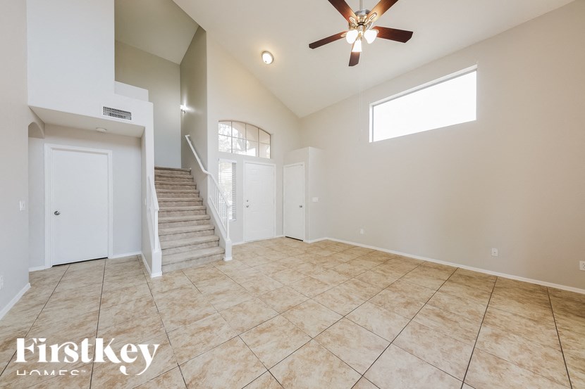 A spacious room with a staircase and a ceiling fan.