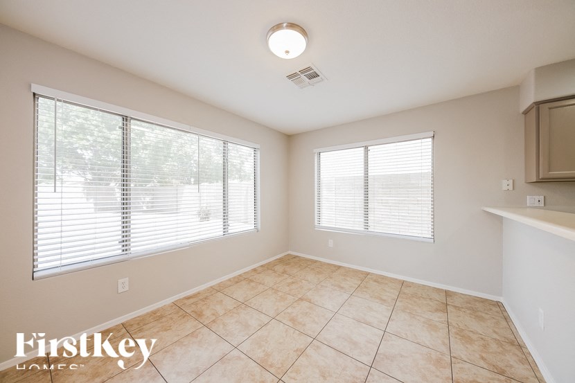 A room with a tiled floor and two windows covered with blinds.