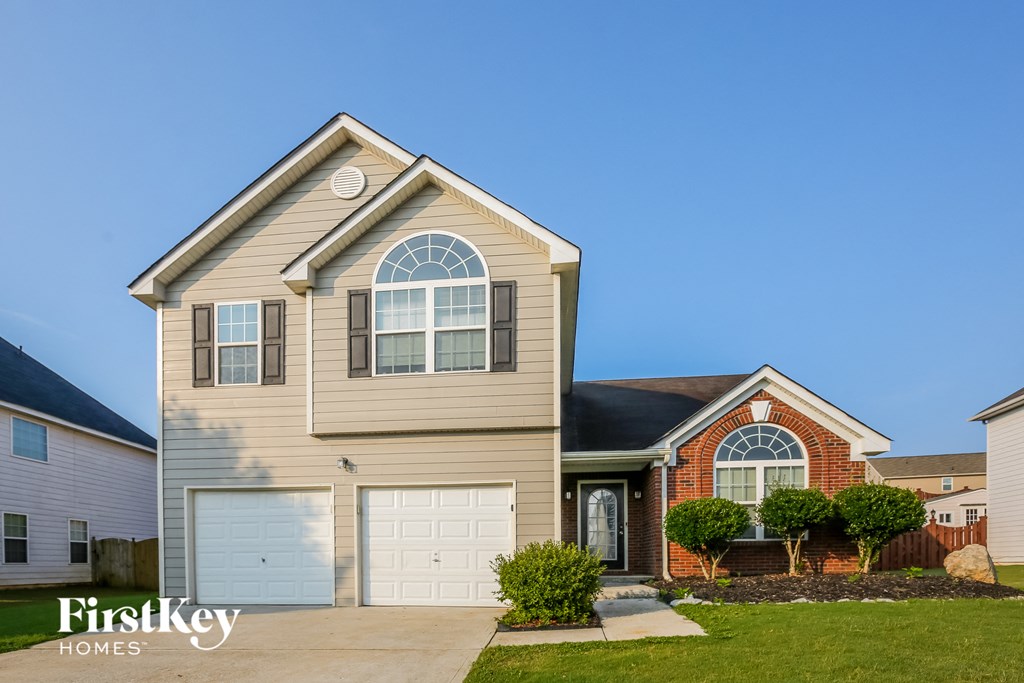 a tan house with a white garage door and a red brick house