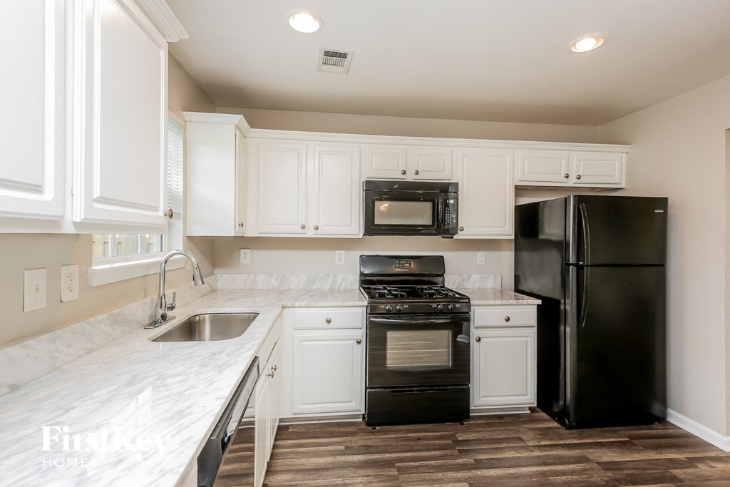 a kitchen with white cabinets and black appliances