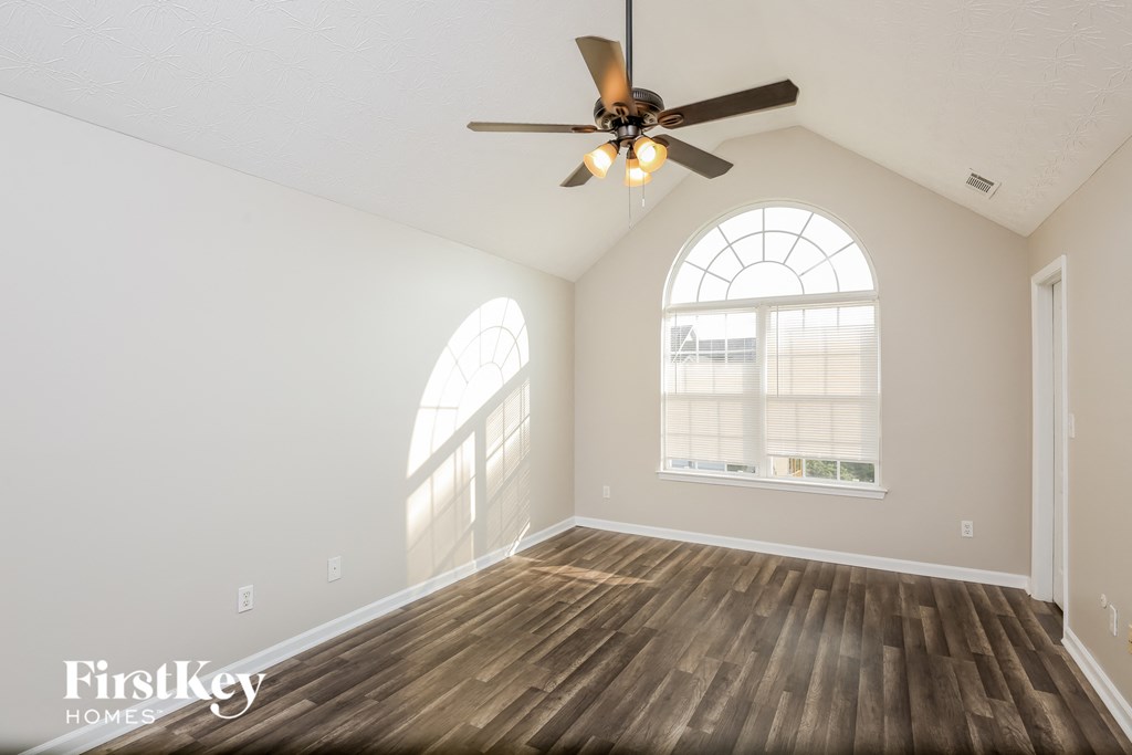 an empty living room with a ceiling fan and a window