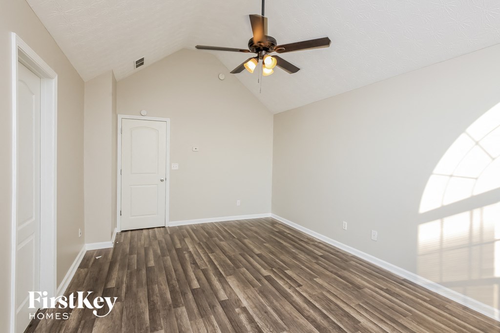the spacious living room with hardwood flooring and a ceiling fan
