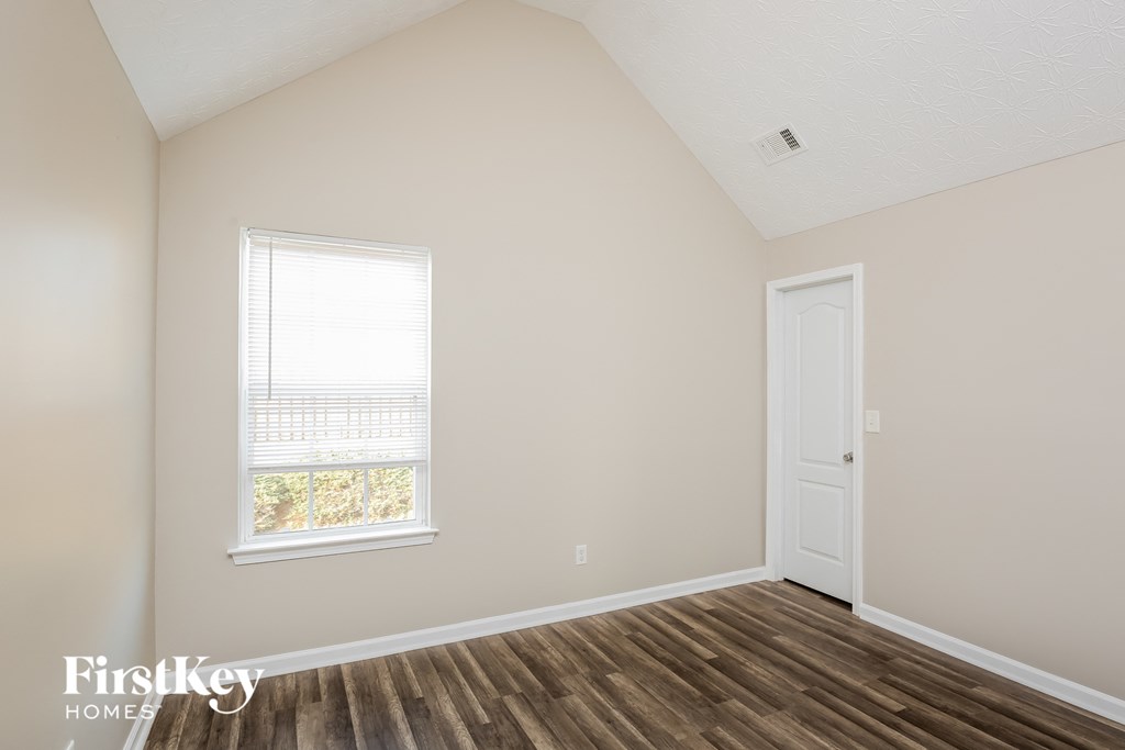 a bedroom with wood floors and a window and a door