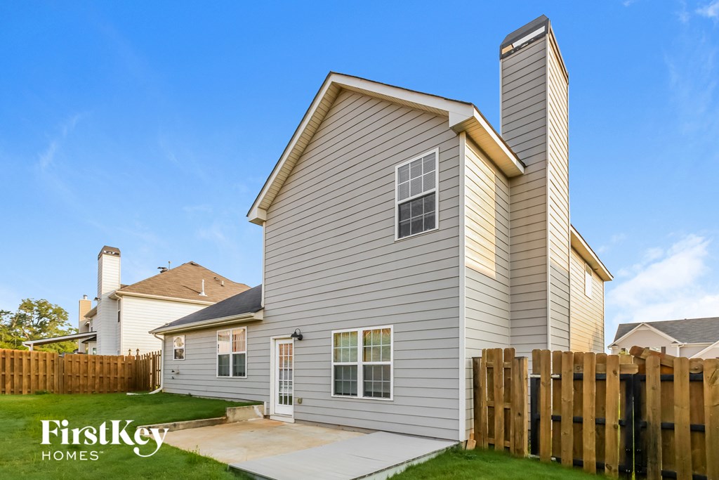 a home with a wooden fence and a grey house