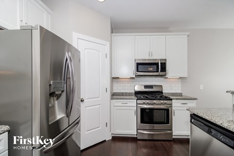 A kitchen with a stainless steel refrigerator and a microwave above the stove.