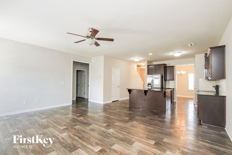 a living room and kitchen with wood flooring and a ceiling fan