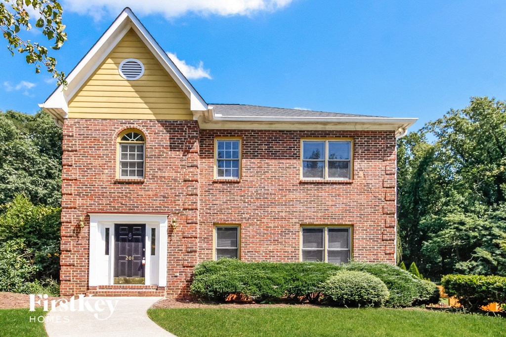 a red brick house with a white door and yellow roof