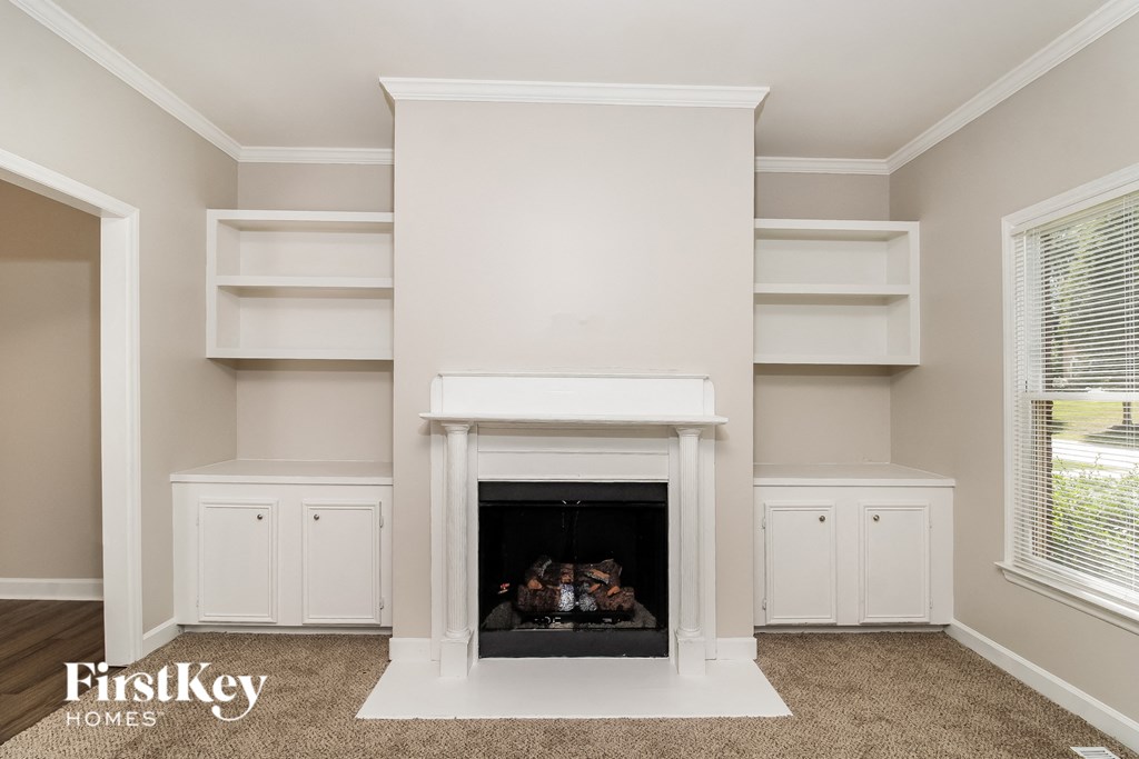 a living room with a fireplace and white shelves