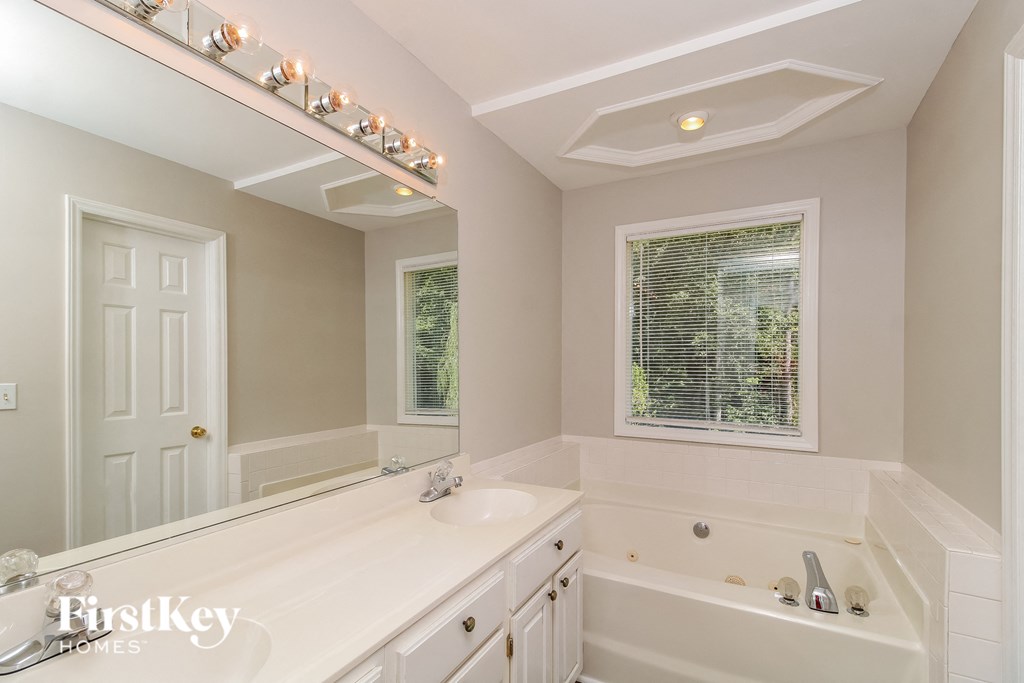 a white bathroom with a tub and a sink and a mirror