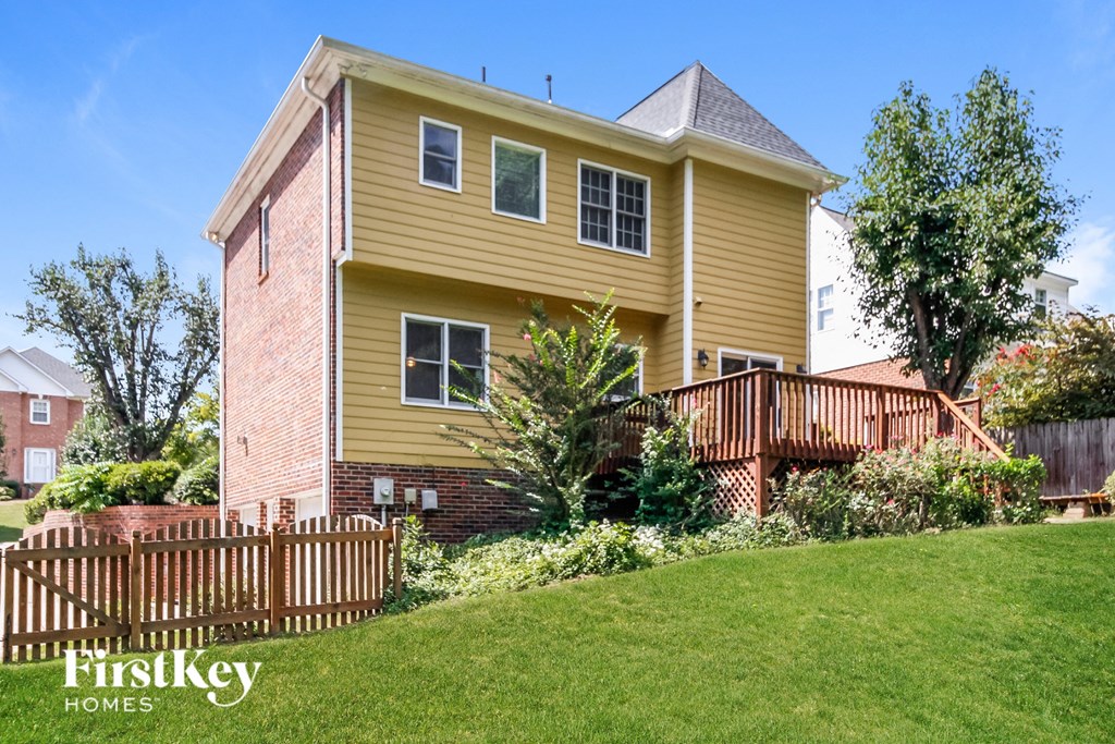 a yellow house with a deck and a wooden fence