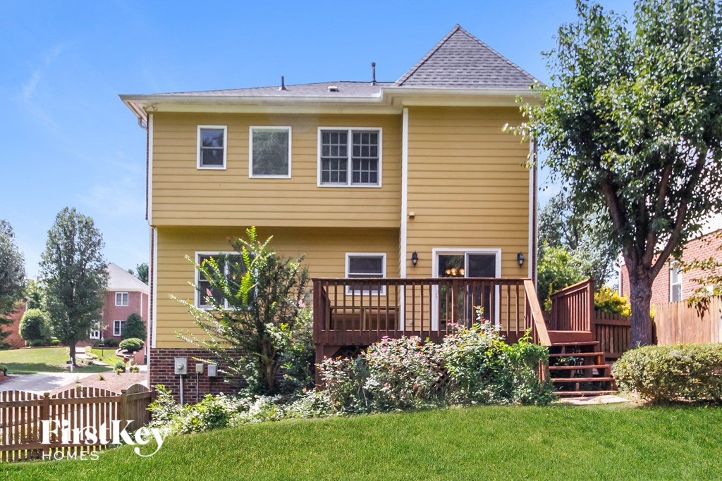 a yellow house with a deck and a yard