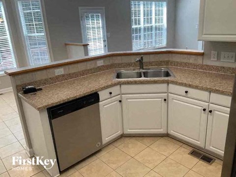 A kitchen with a sink, dishwasher, and cabinets.