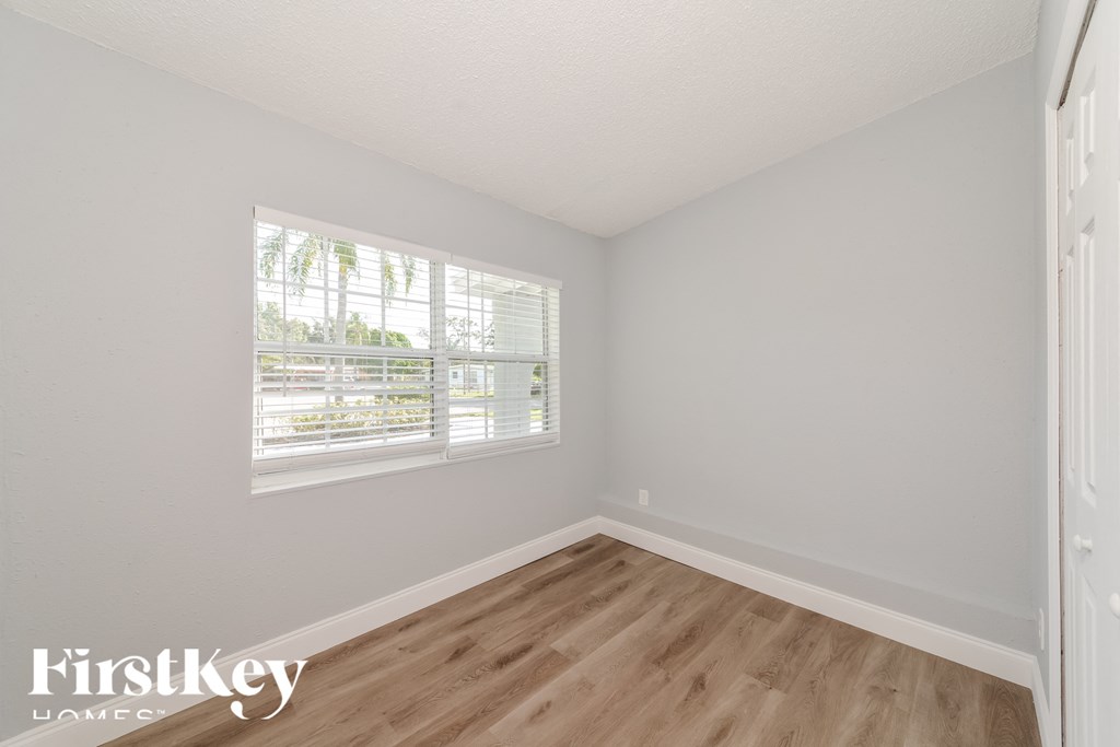 a bedroom with wood floors and white walls and a window