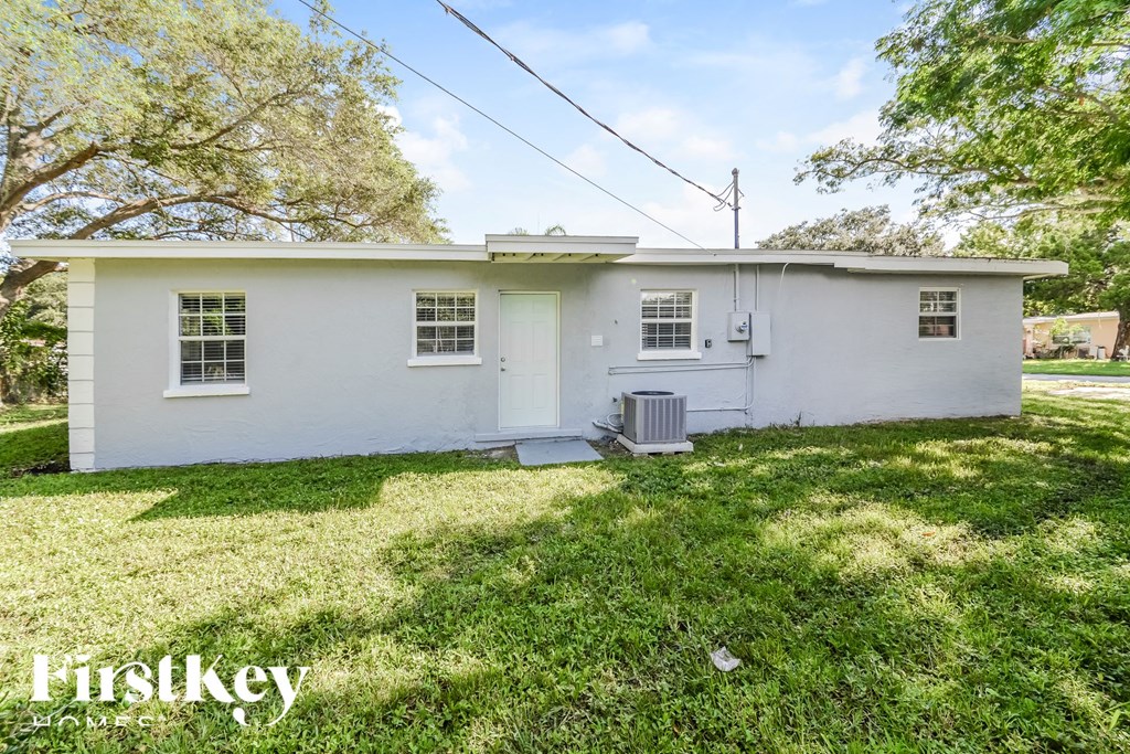 a small white house with a grass yard and trees