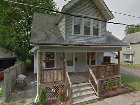 A small house with a porch and a wooden fence.