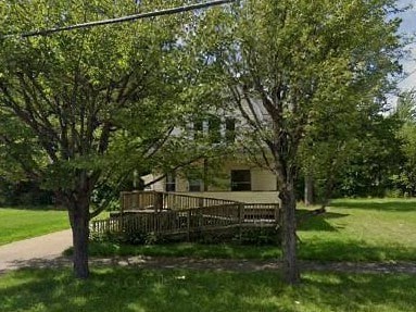 A house with a deck and trees in front.