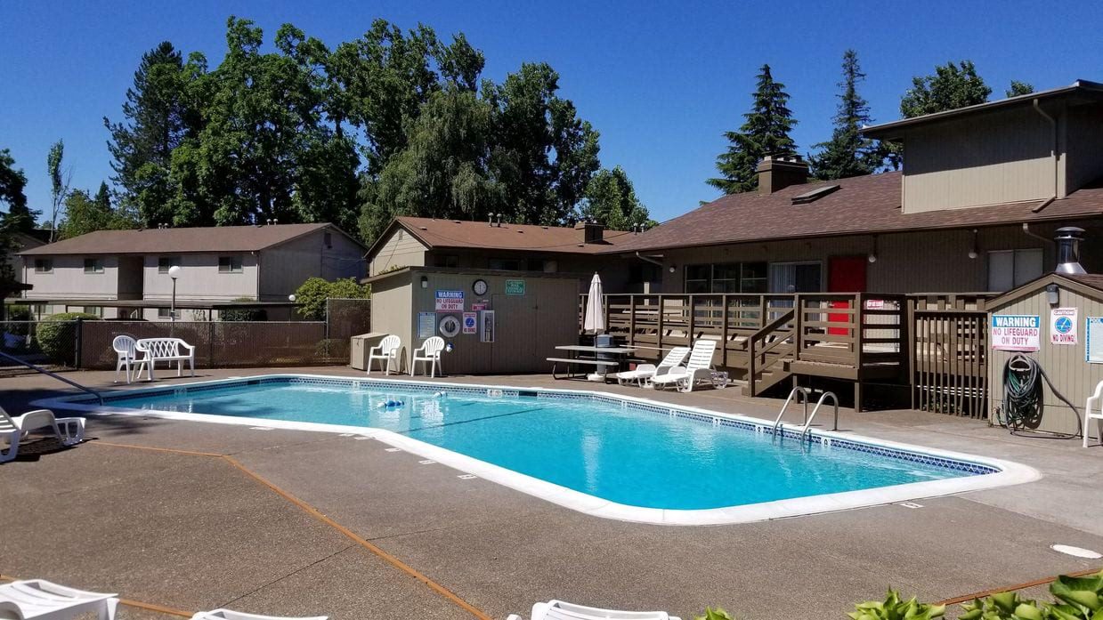 a swimming pool with chairs around it in front of a building