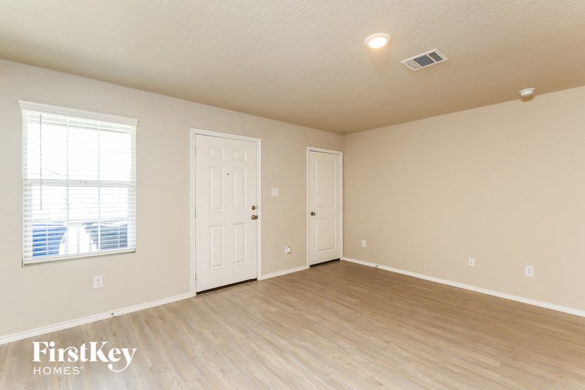 the living room of an empty house with a door and a window