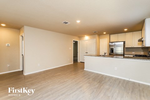 an open kitchen and living room with wood floors and white cabinets
