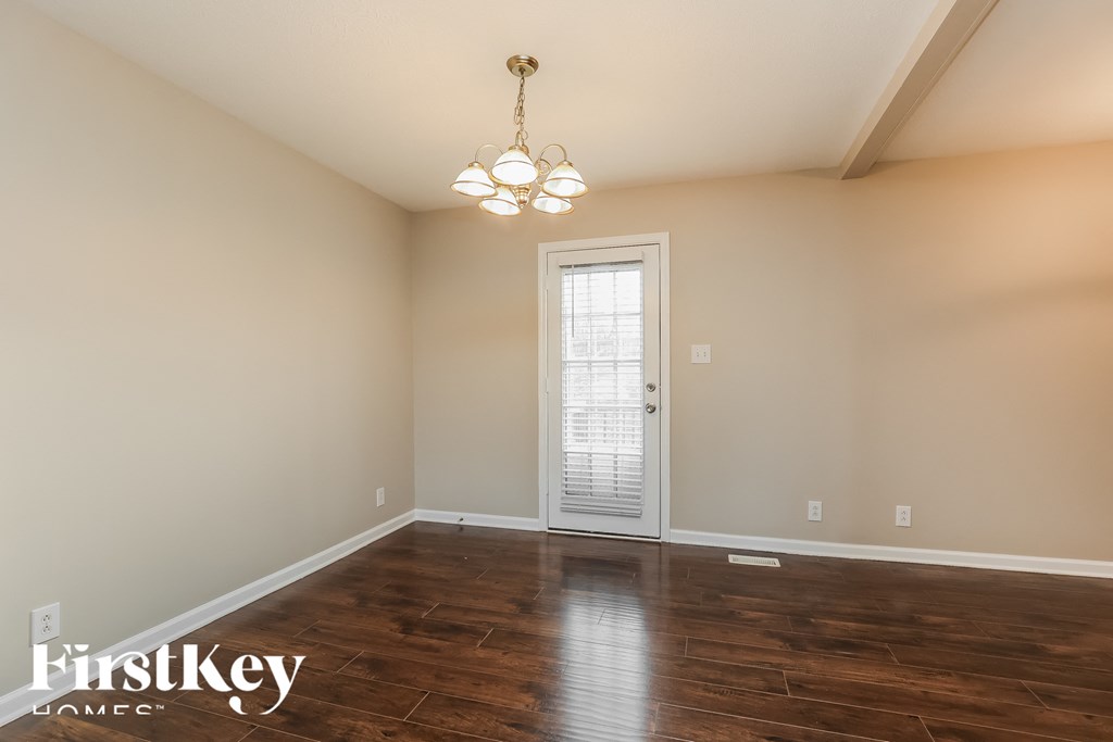 a empty living room with wood floors and a chandelier