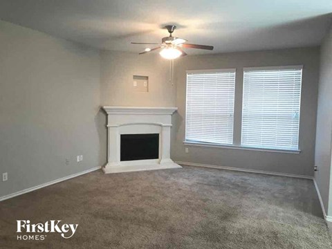 A living room with a fireplace and a ceiling fan.