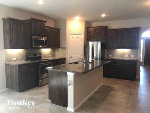 A kitchen with dark wood cabinets and a granite countertop.