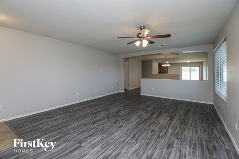 an empty living room with a ceiling fan and a window