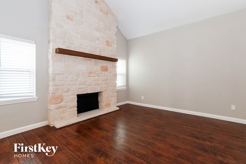 a living room with a stone fireplace and wooden floors