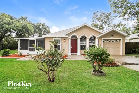 the front of a house with a lawn and two trees