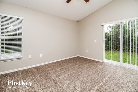 a spacious living room with a large window and carpeted flooring
