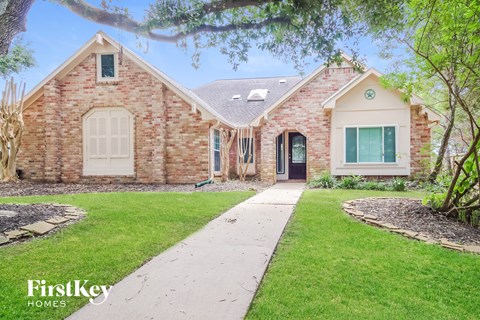 front view of a brick house with green grass and a sidewalk