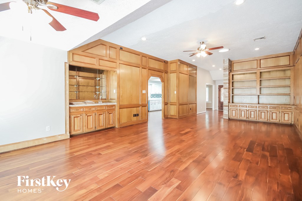 a large living room with wood flooring and wooden cabinets