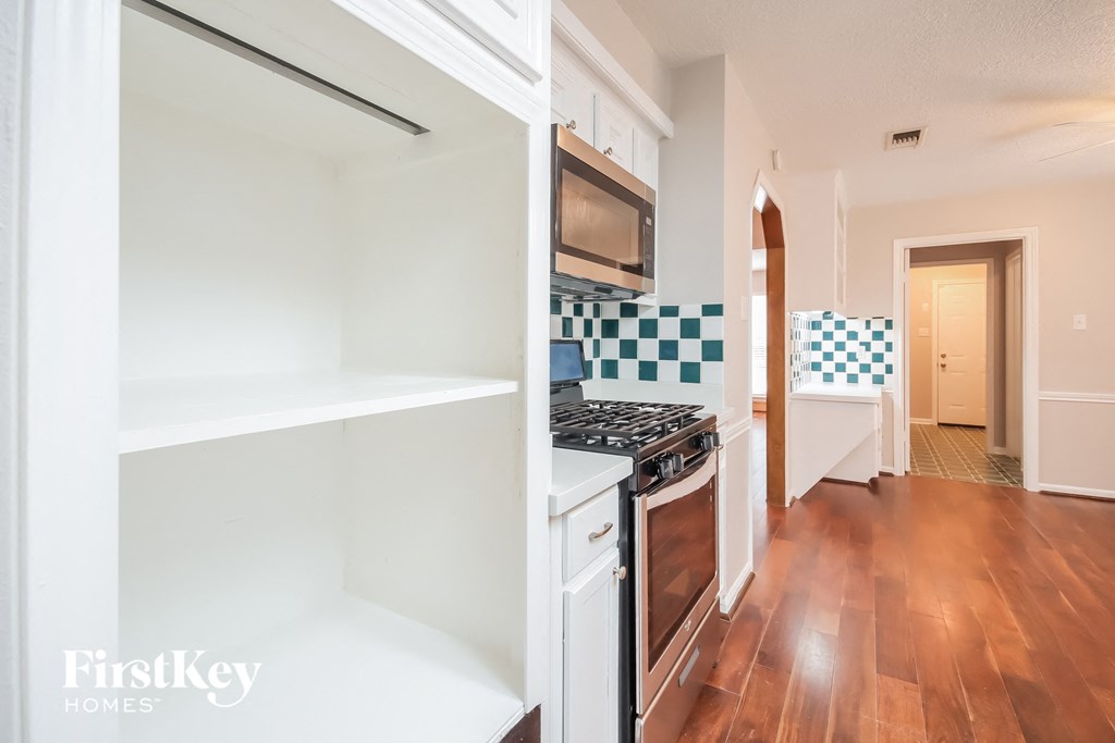 a kitchen with white cabinets and a stove and a microwave