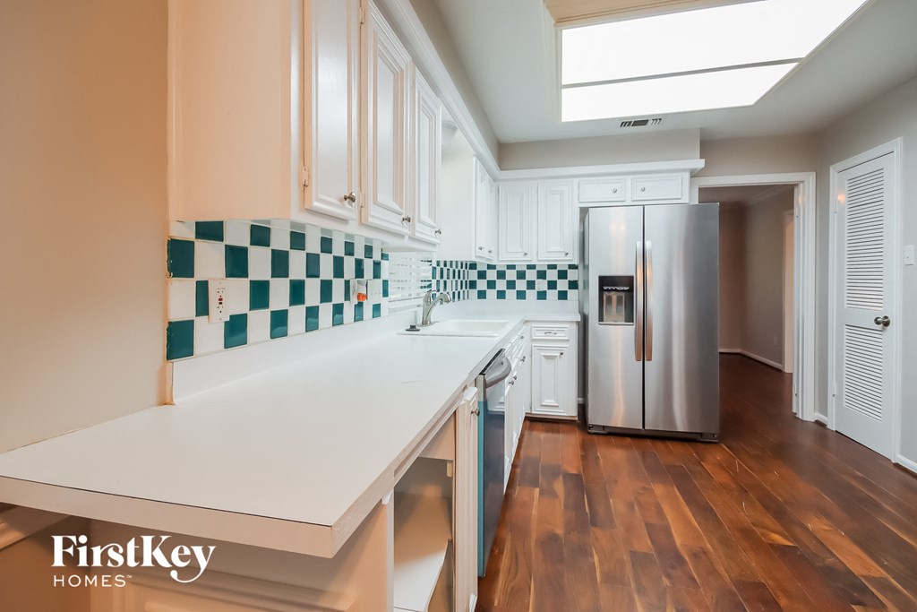 a kitchen with white countertops and a stainless steel refrigerator