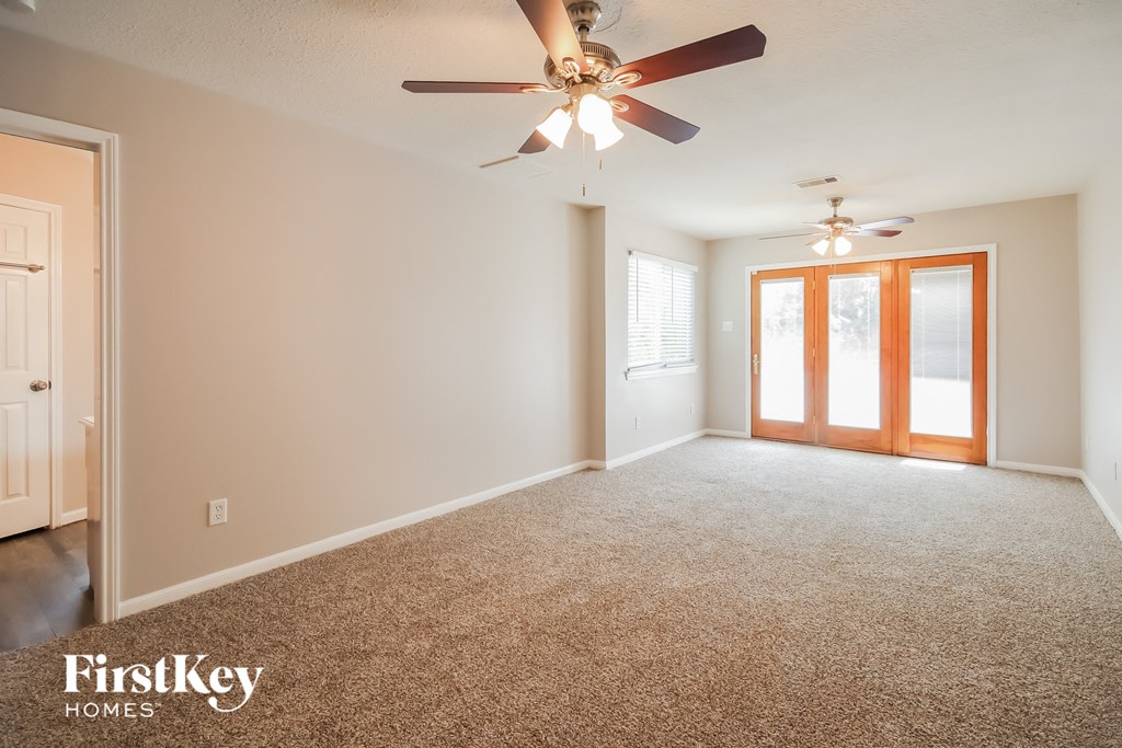 an empty living room with a ceiling fan