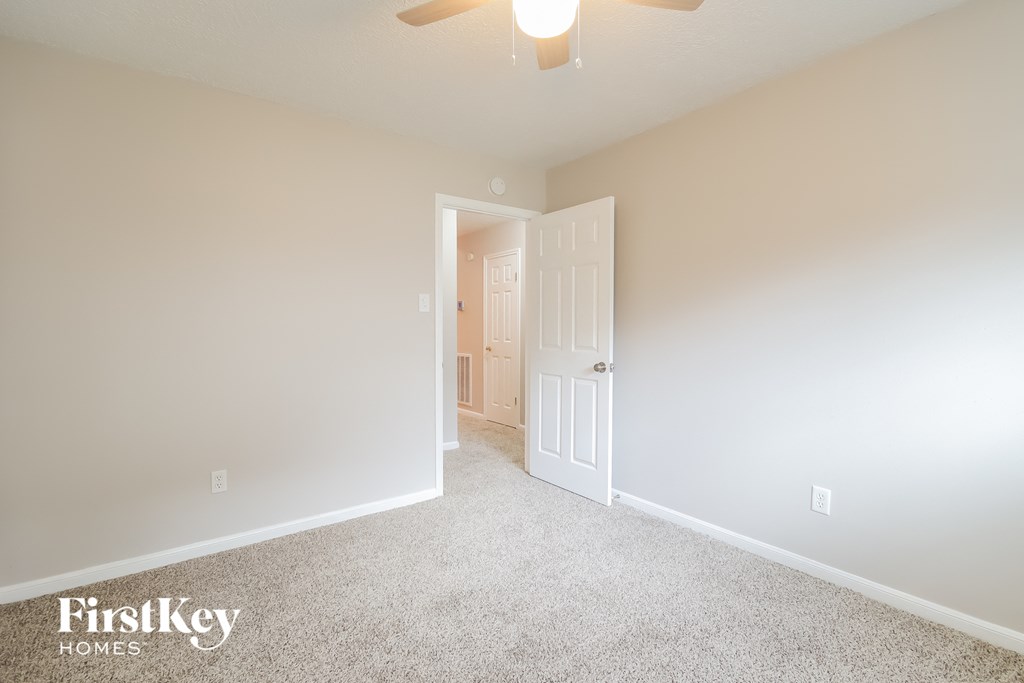 a bedroom with white carpet and a ceiling fan
