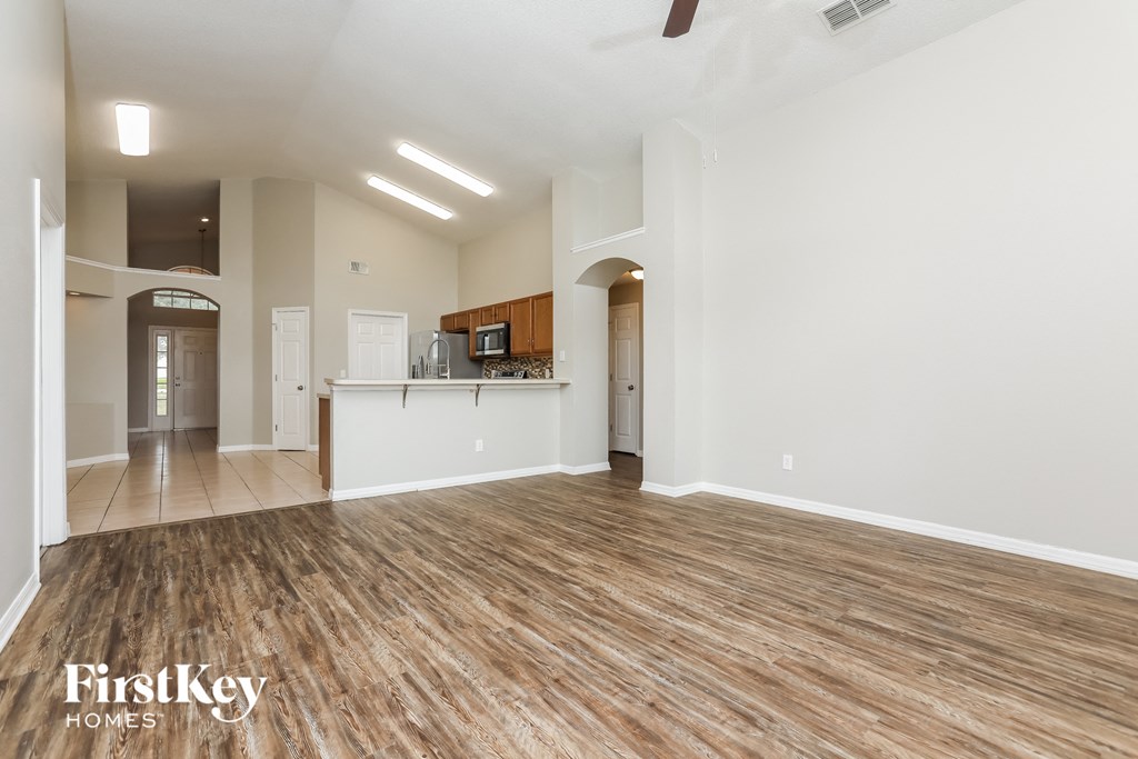 the living room and kitchen of an empty house with wood flooring