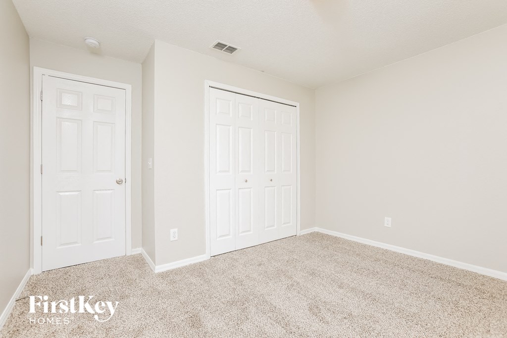 a bedroom with two doors and a carpeted floor