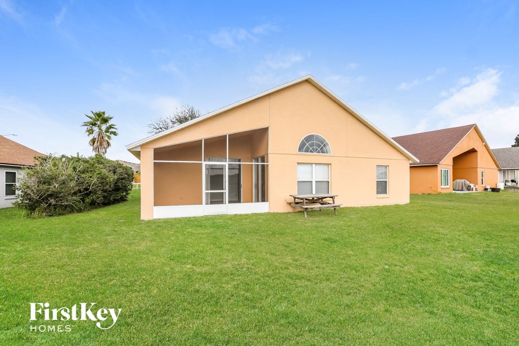 the outside of a house with a lawn and a table