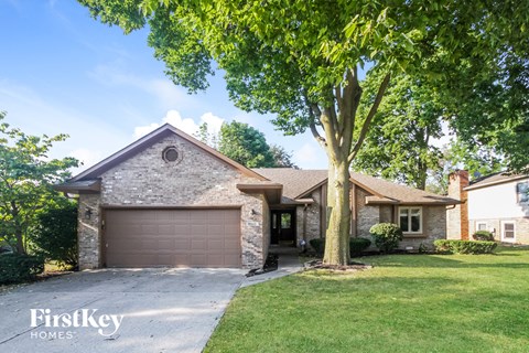 a brick house with a garage and a tree