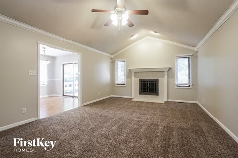 an empty living room with a fireplace and a ceiling fan