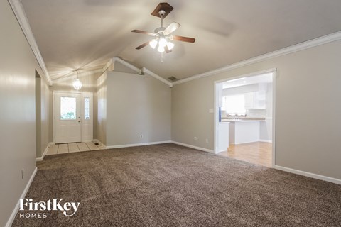 an empty living room with a ceiling fan and a rug